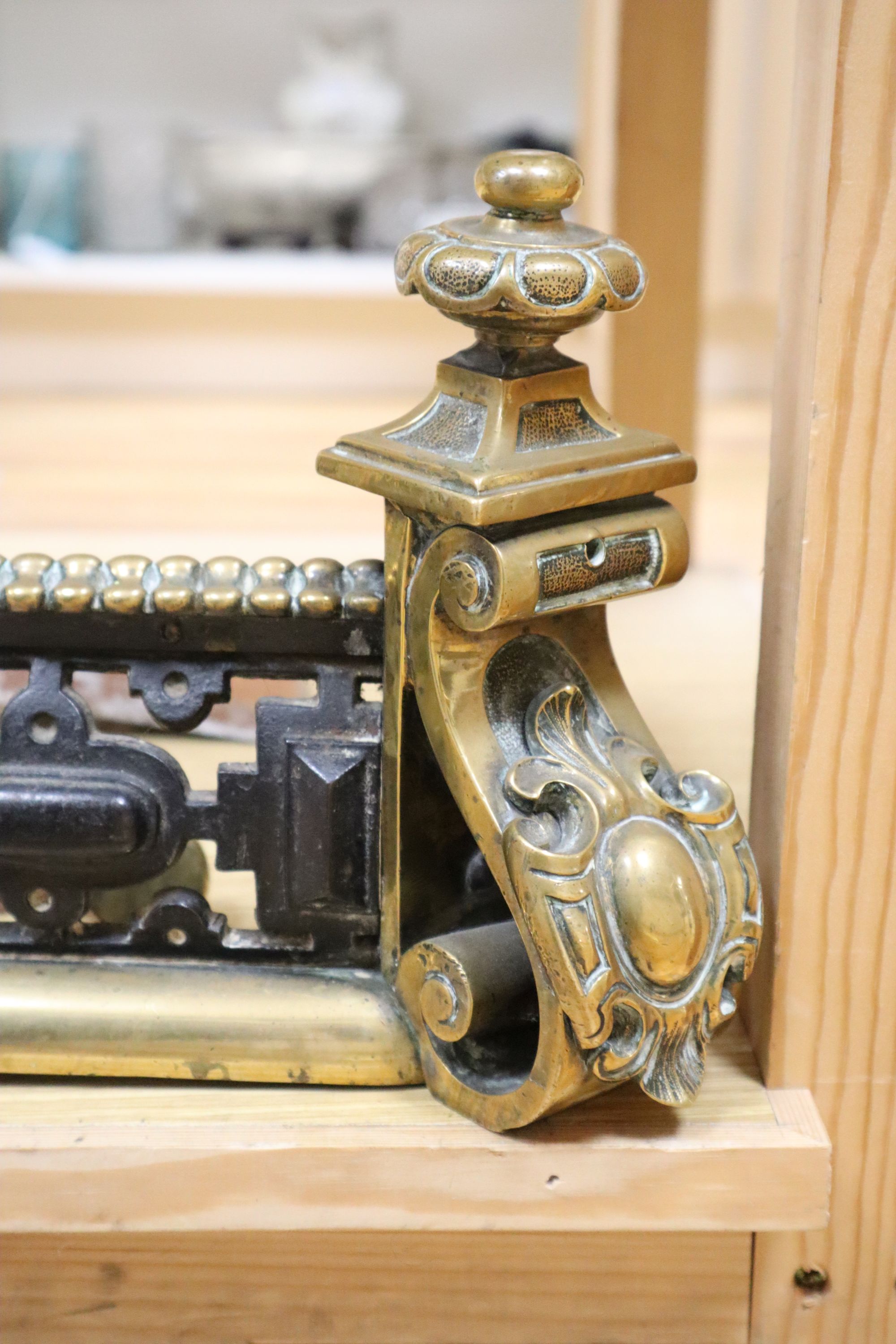 A Victorian brass and cast iron pierced fender and a three-piece set of later fire irons
